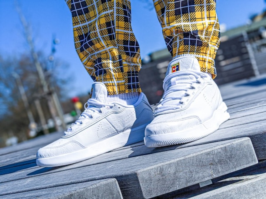 Weiße Sneaker angezogen mit gelb/weiß/schwarz karierter Hose